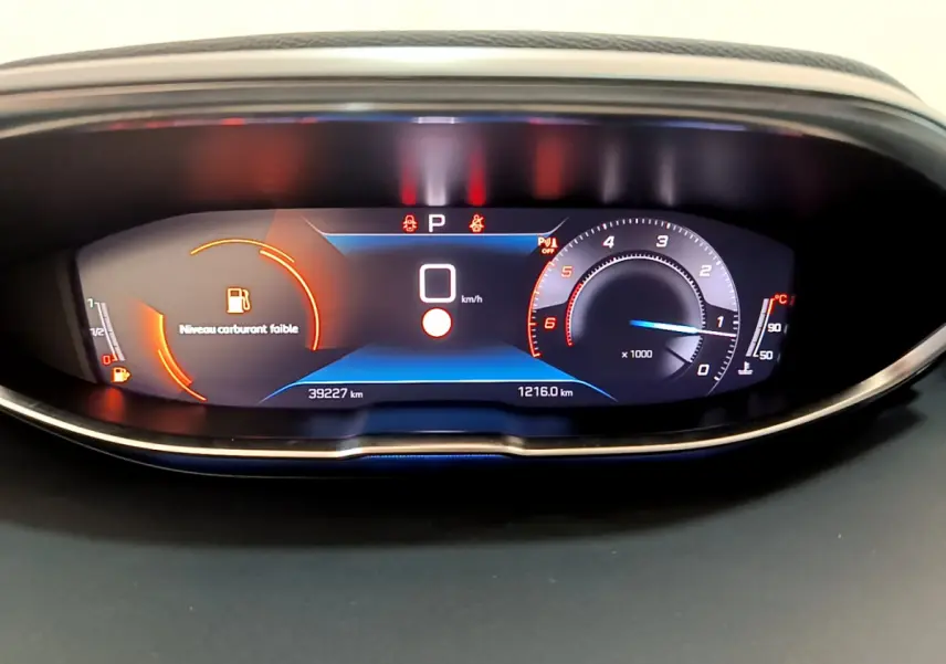 Tableau de bord numérique du Peugeot 3008 noir 2022 affichant vitesse zéro et avertissement niveau carburant faible.