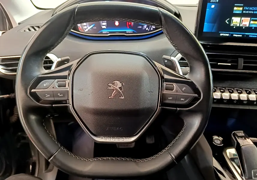Vue rapprochée du volant cuir noir de la Peugeot 3008 2022 avec commandes intégrées et tableau de bord digital.