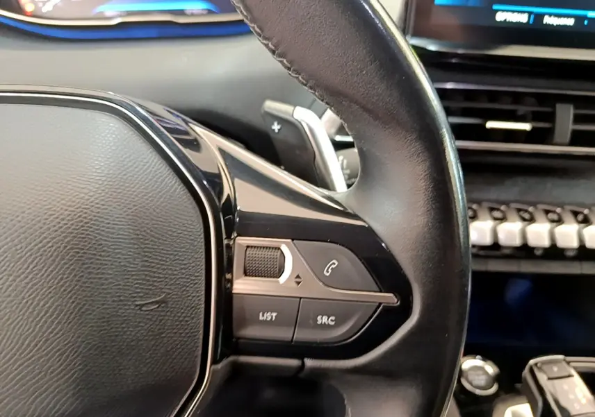 Gros plan sur le volant cuir noir de la Peugeot 3008 2022 avec commandes audio intégrées côté droit.