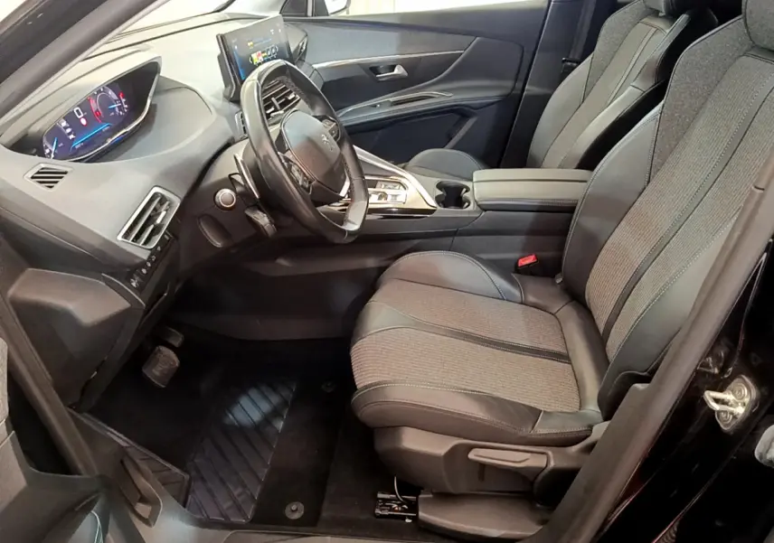 Intérieur côté conducteur du Peugeot 3008 noir 2022, avec tableau de bord numérique et sièges tissu-cuir gris.