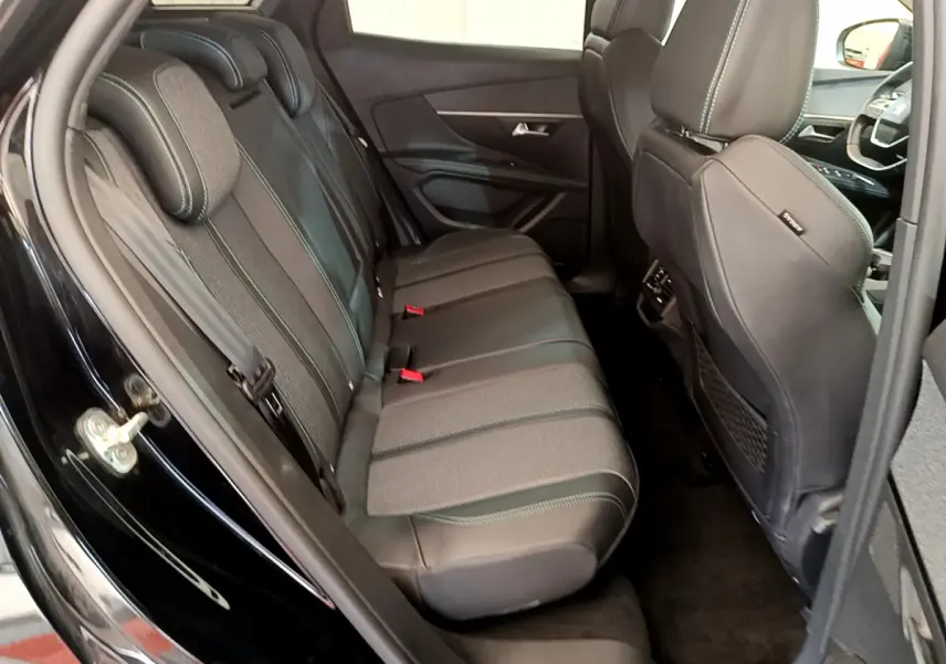Vue intérieure côté gauche sur la banquette arrière en cuir et tissu du Peugeot 3008 noir, avec sièges avant partiellement visibles.
