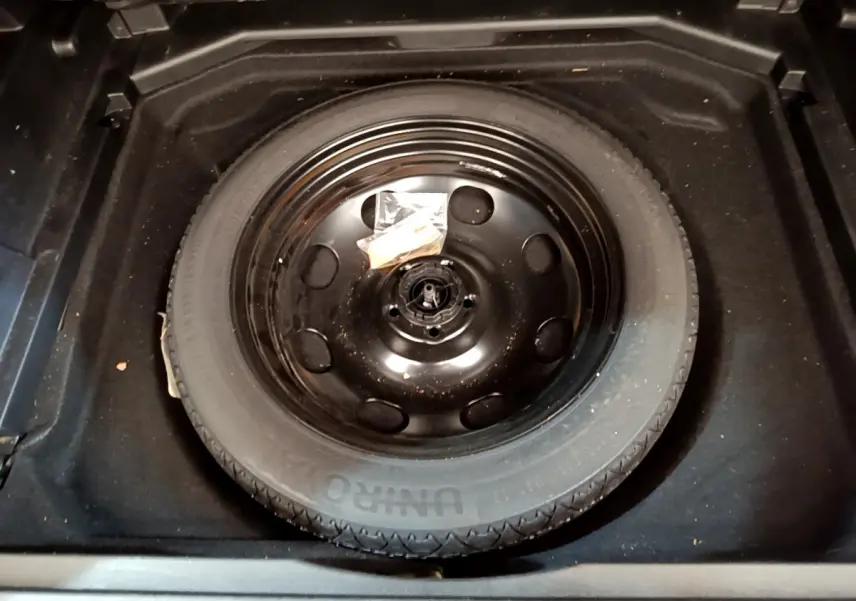 Vue plongeante sur la roue de secours noire dans le coffre du Peugeot 3008 BlueHDi 130 S&S EAT8 Allure Pack 2022.