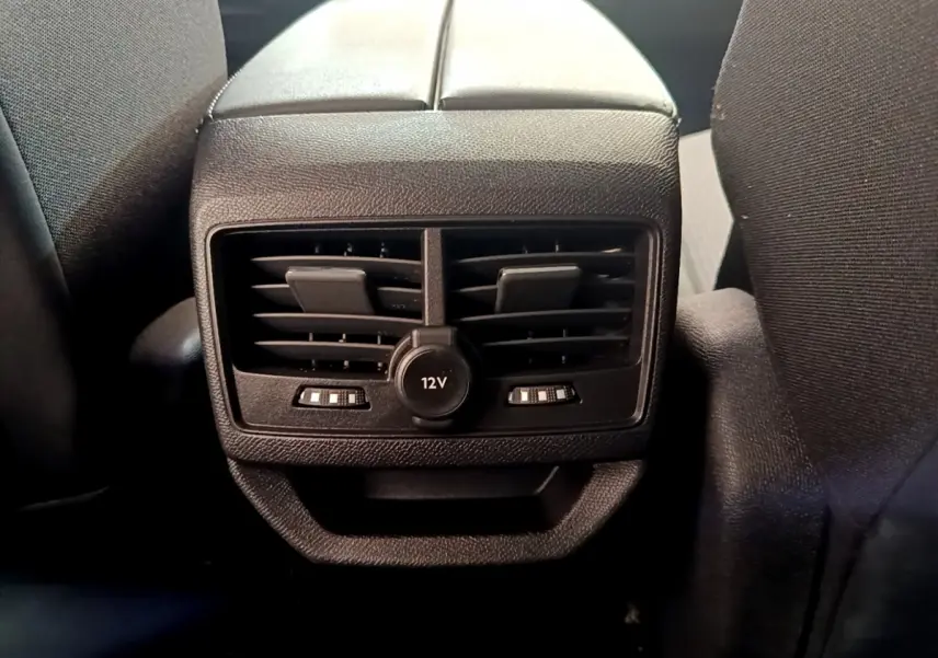 Gros plan sur la prise 12V et les aérateurs arrière noirs entre les sièges du Peugeot 3008 noir 2022.