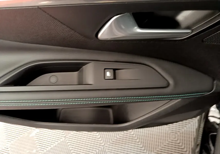 Gros plan sur la poignée intérieure côté gauche de la porte noire du Peugeot 3008 avec surpiqûres bleues.