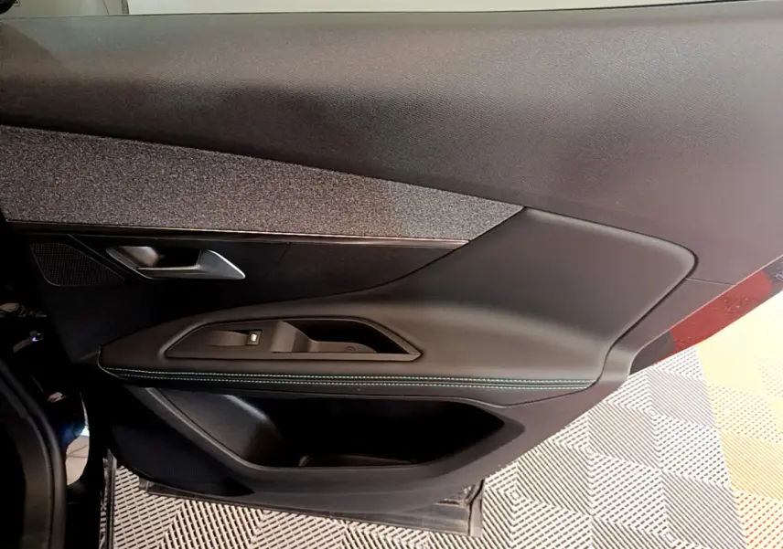Gros plan sur la porte intérieure côté gauche du Peugeot 3008 noir, avec poignée et commandes de vitre intégrées.
