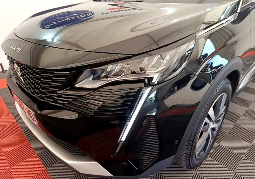 Vue 3/4 avant droit d'un Peugeot 3008 noir avec phares LED et calandre distinctive en intérieur showroom.