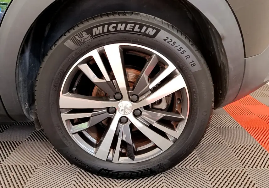 Gros plan sur la roue avant droite du Peugeot 3008 noir, mettant en valeur la jante alliage et le pneu Michelin.
