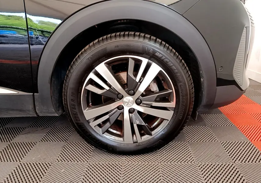 Gros plan sur la roue avant gauche du Peugeot 3008 noir, mettant en valeur la jante alliage et le pneu Michelin.