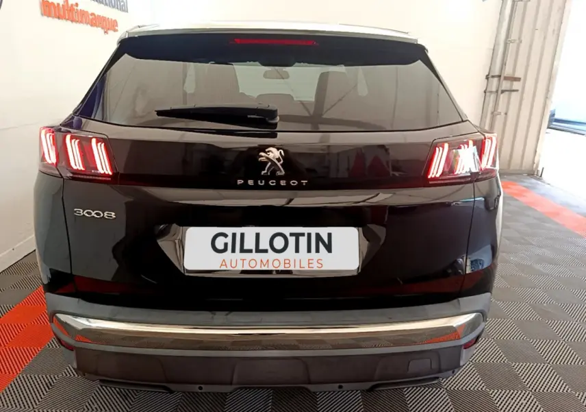 Vue arrière d'un Peugeot 3008 noir avec feux LED caractéristiques et logo central dans un garage.