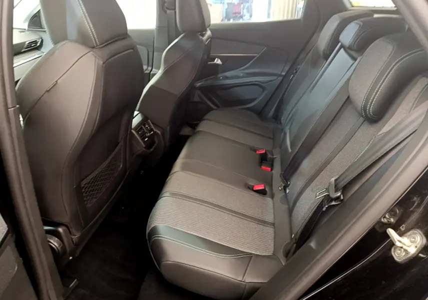 Vue côté droit de l'intérieur arrière du Peugeot 3008 noir 2022 avec sièges en cuir et tissu gris à surpiqûres blanches.