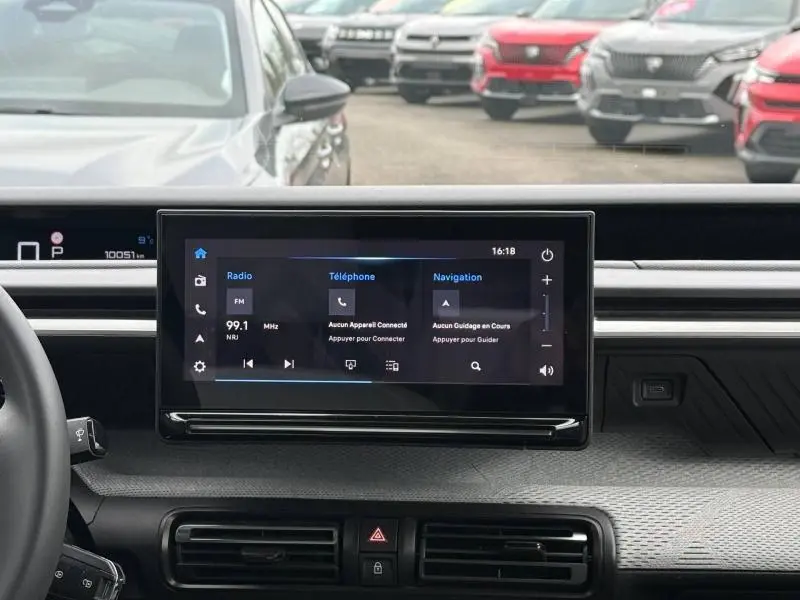 Vue intérieure centrée sur l'écran tactile du tableau de bord de la Citroën C3 électrique 2025, avec volant à gauche visible.