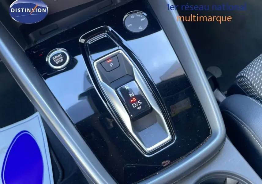 Gros plan sur la console centrale noire brillante avec levier de vitesses électronique et bouton start/stop d'une Audi A3 Sportback 2025.