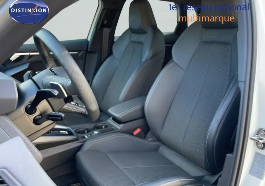 Vue intérieure côté conducteur de l'Audi A3 Sportback blanc Ibis, sièges sport gris foncé avec logo S embossé.
