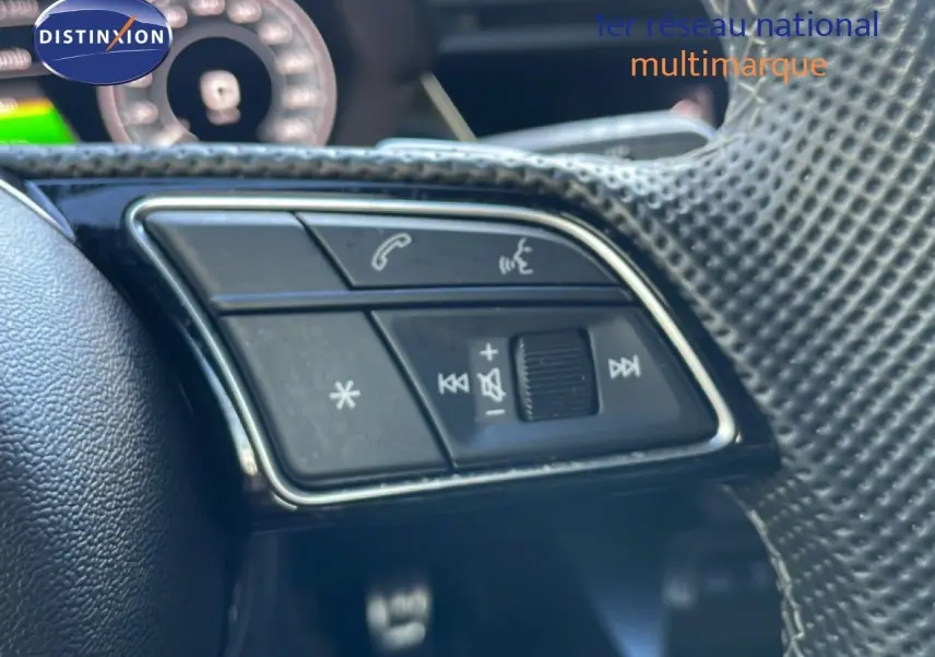 Gros plan sur les commandes du volant à droite de l'Audi A3 Sportback 40 TFSIe blanc Ibis, intérieur gris-noir.