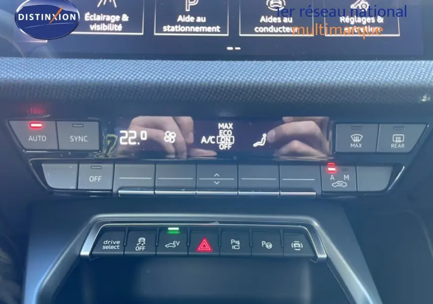 Gros plan sur la console centrale de l’Audi A3 Sportback blanc Ibis 2025, mettant en valeur les commandes climatisation et aides à la conduite.