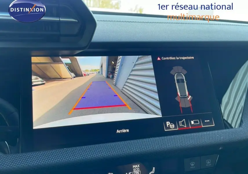 Écran de caméra de recul affichant la trajectoire d’une Audi A3 Sportback blanche vue de l’arrière, tableau de bord visible.