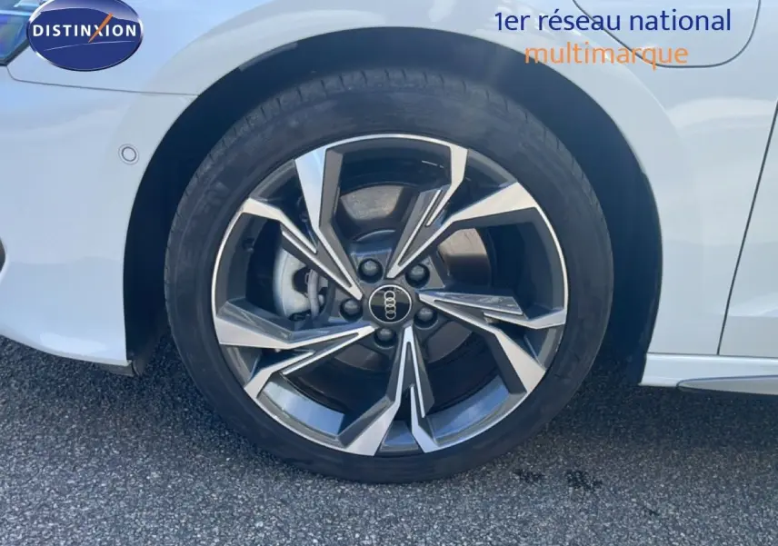 Gros plan sur la roue avant droite d’une Audi A3 Sportback blanc ibis avec jante alliage au design moderne.