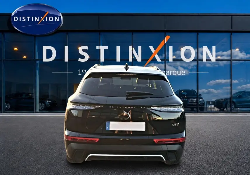 Vue arrière d'un SUV DS7 noir 2026 garé devant une vitrine avec logo Distinxion en arrière-plan.