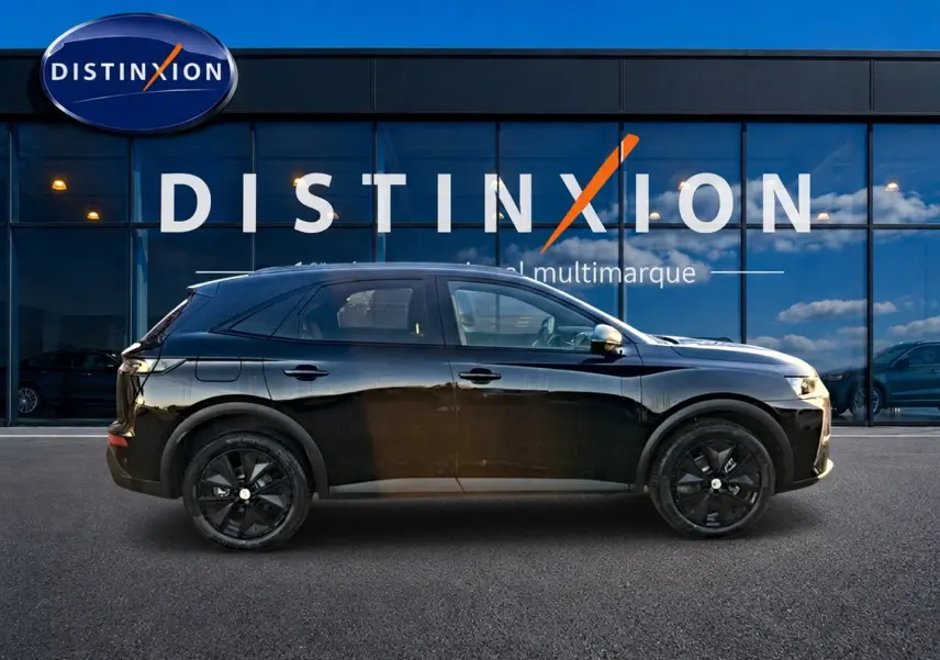 Vue latérale droite du SUV DS7 noir brillant avec jantes noires, devant une vitrine Distinxion multimarque.