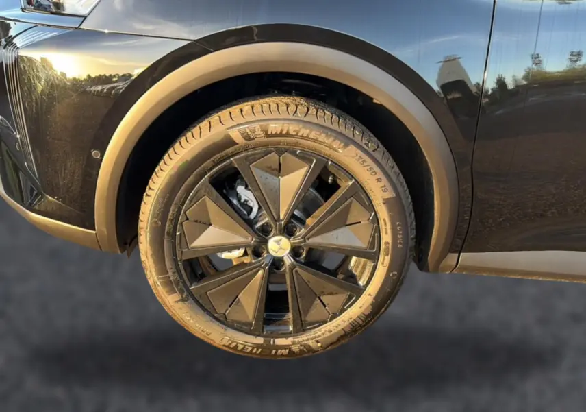 Gros plan sur la roue avant gauche noire du DS7 1.5 BlueHDi 130 avec jante alu noire au design géométrique.