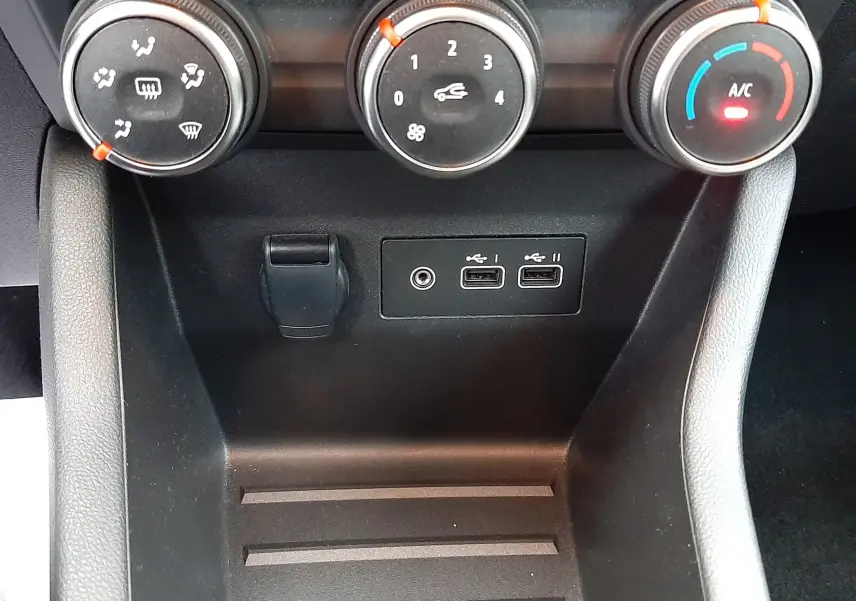 Vue rapprochée des commandes de climatisation et des ports USB sur la console centrale d'une Renault Clio V gris schiste.