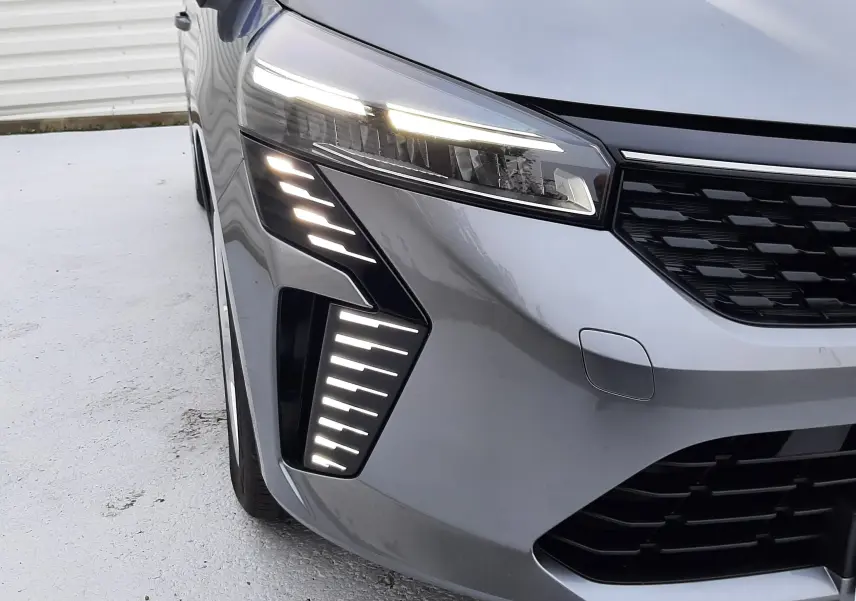 Vue avant gauche d'une Renault Clio V TCE 90CH Evolution gris schiste avec feux LED distinctifs allumés.