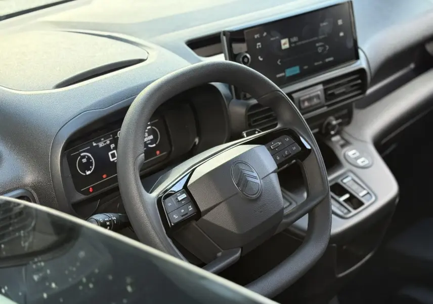 Vue rapprochée du volant multifonctions et tableau de bord numérique du Citroën Berlingo gris Artense 2025.