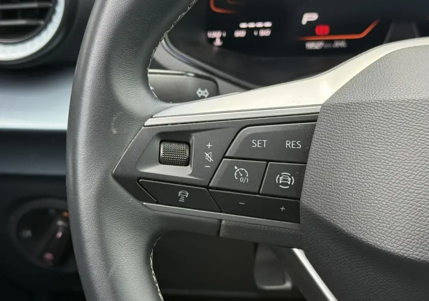 Gros plan sur les commandes du régulateur de vitesse au volant d’un SEAT Arona 2025, intérieur noir.