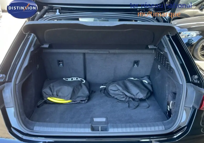 Coffre ouvert vu de l'arrière d'une Audi A3 Sportback noir mito metal avec deux sacs noirs à l'intérieur.