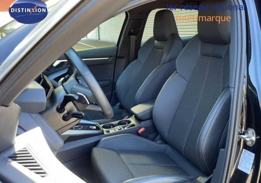 Vue intérieure côté conducteur de l'Audi A3 Sportback 40 TFSIe S-Line 2025 avec sièges cuir noir et volant multifonction.