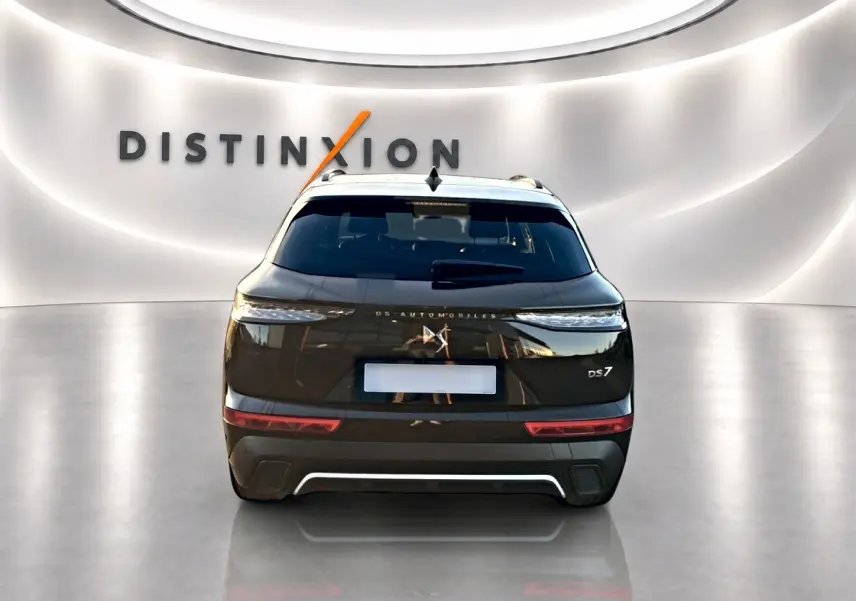 Vue arrière d'un DS7 noir 2026 avec feux LED étirés et double sortie d'échappement dans un showroom lumineux.