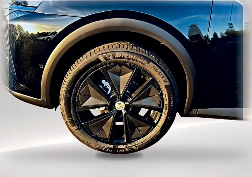Gros plan sur la roue avant gauche noire du DS7 1.5 BlueHDi 130 avec jante alu noire au design géométrique.