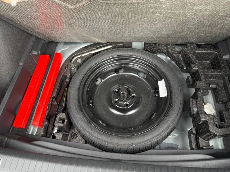Vue plongeante sur la roue de secours et les outils de bord dans le coffre du CUPRA Formentor 1.5 eTSI Hybrid 2025.