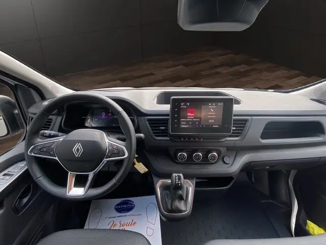 Vue intérieure du tableau de bord du Renault Trafic Fourgon 2025, avec volant multifonction noir et écran tactile central.