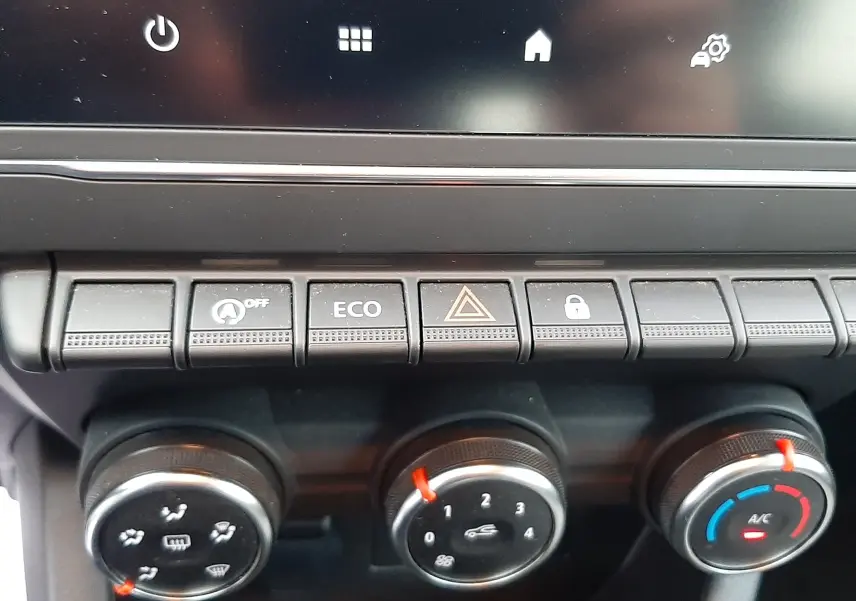 Gros plan sur les commandes de climatisation et boutons fonctionnels du tableau de bord d'une Renault Clio V gris schiste.