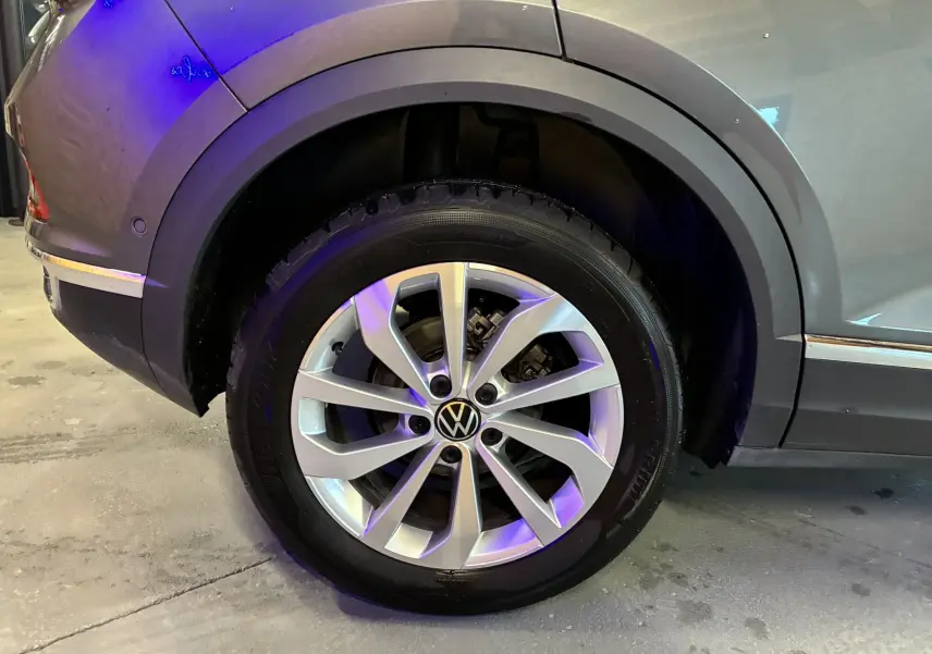 Gros plan sur la roue arrière droite gris métallisé du Volkswagen T-Roc 2023 avec jante alliage et logo VW central.