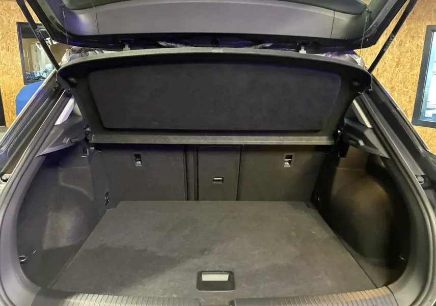 Vue intérieure du coffre ouvert d'un Volkswagen T-Roc gris 2023, montrant l'espace de chargement et la tablette arrière.