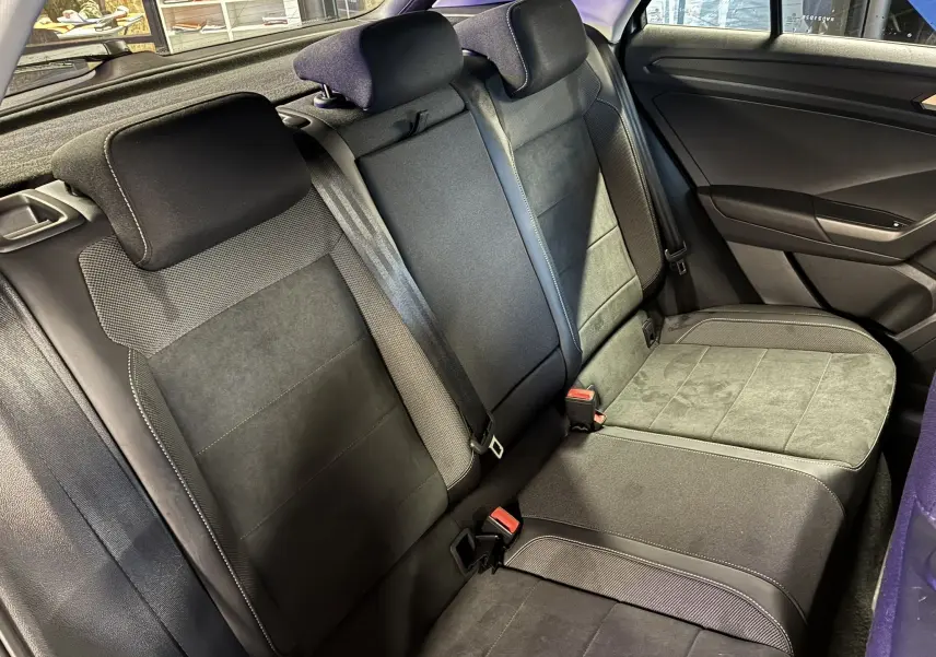 Vue intérieure côté droit des sièges arrière en tissu noir du Volkswagen T-Roc 2023, avec ceinture de sécurité et porte visible.