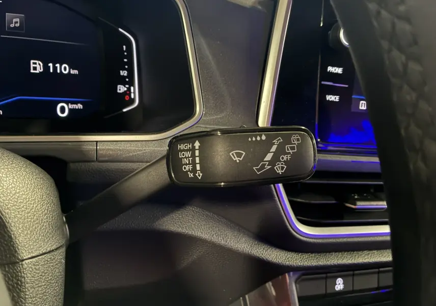 Gros plan sur la commande d’essuie-glace côté droit du tableau de bord du Volkswagen T-Roc gris 2023, avec affichage numérique en arrière-plan.