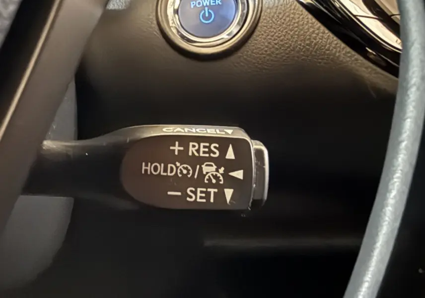 Gros plan sur la commande du régulateur de vitesse au volant cuir du Toyota C-HR gris foncé 2022.