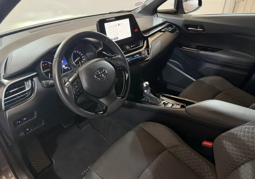 Vue intérieure côté conducteur du Toyota C-HR 1.8 Hybride 2022 avec tableau de bord numérique et écran tactile central.