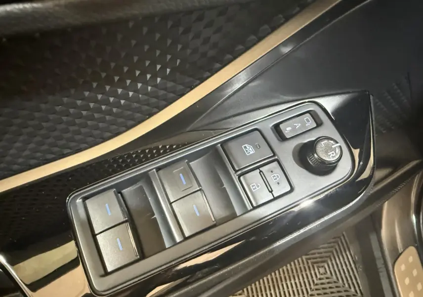 Gros plan sur les commandes de lève-vitres et rétroviseurs noirs dans l'habitacle du Toyota C-HR gris foncé.