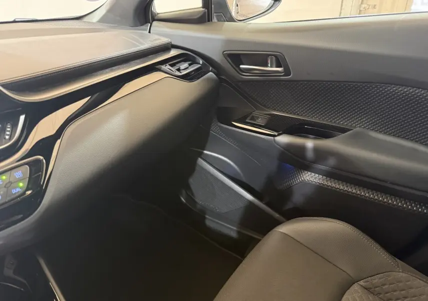 Intérieur côté passager du Toyota C-HR gris foncé 2022, montrant la portière et tableau de bord en matériaux noirs.