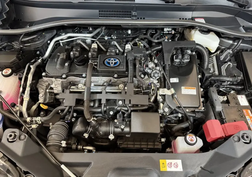 Vue plongeante sur le moteur hybride Toyota C-HR 1.8 gris foncé, avec logo Toyota visible au centre du moteur.