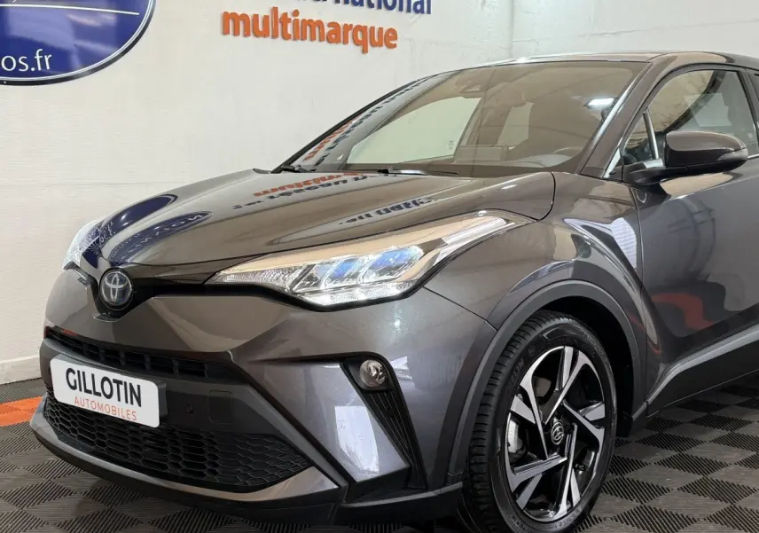 Vue 3/4 avant droit d'un Toyota C-HR 1.8 Hybride gris foncé avec phares LED et jantes alliage noires.
