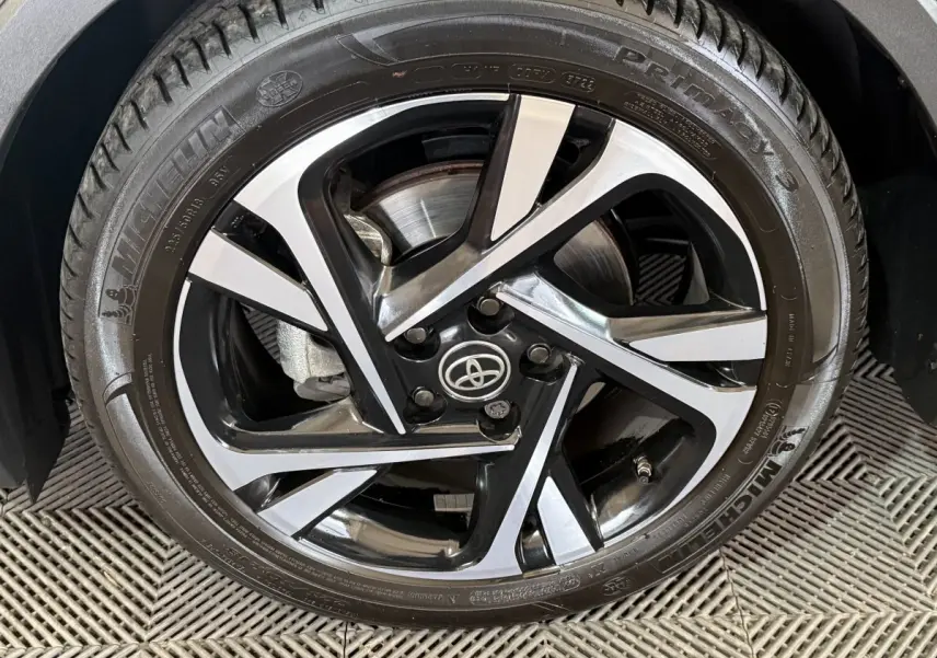 Gros plan sur la jante alliage bicolore noire et argentée d’un Toyota C-HR gris foncé, roue avant droite.