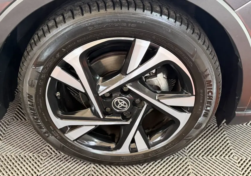 Gros plan sur la jante alliage noire et argentée du Toyota C-HR gris foncé, avec pneu Michelin visible.
