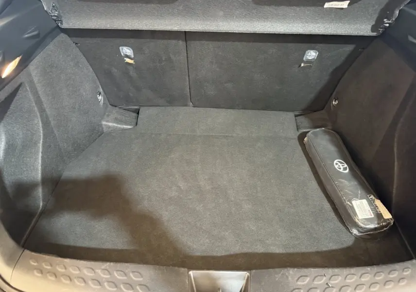 Coffre spacieux vu de face, intérieur noir avec trousse à outils Toyota sur le côté droit.