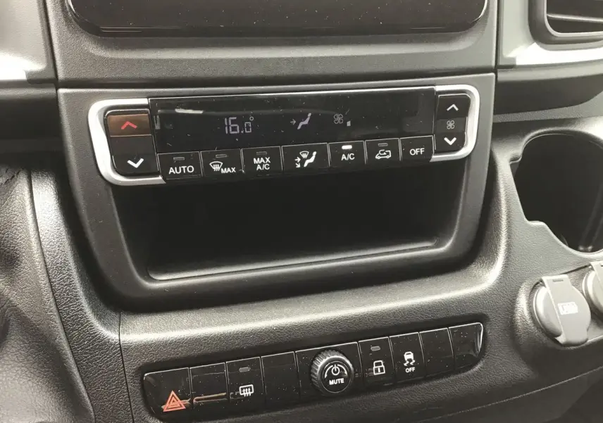 Gros plan sur la console centrale du Fiat Ducato Fourgon blanc 2023, mettant en valeur les commandes de climatisation et les boutons multifonctions.