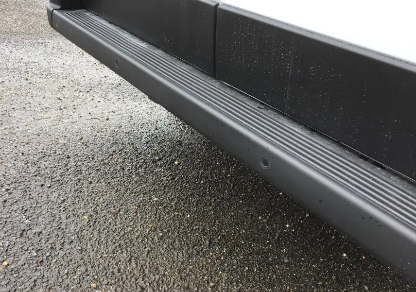 Gros plan sur la marche latérale noire du Fiat Ducato Fourgon blanc, côté droit, avec traces d'eau sur la carrosserie.